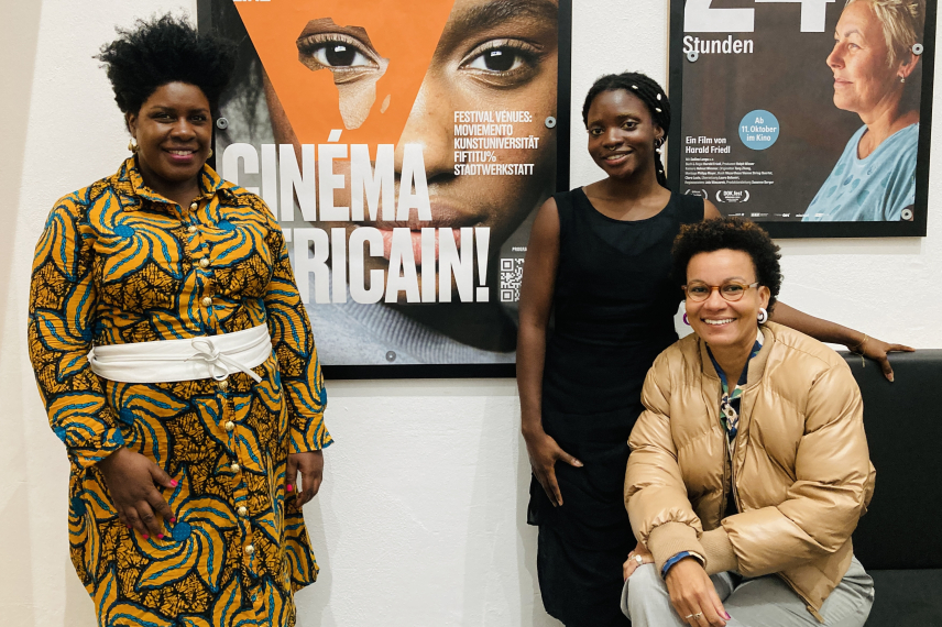 Three persons from cinema world are standing in front of the poster.