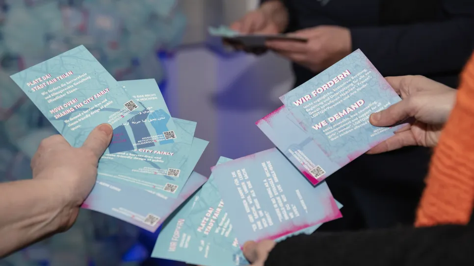 Flyer in Händen mehrerer Personen, Fokus auf Texte über feministische Forderungen.