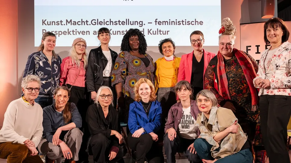 Gruppe von Frauen vor einem Banner mit dem Titel "Kunst. Macht. Gleichstellung."