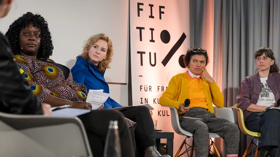 Podiumsdiskussion mit vier Frauen vor "FIFITIO" Banner.
