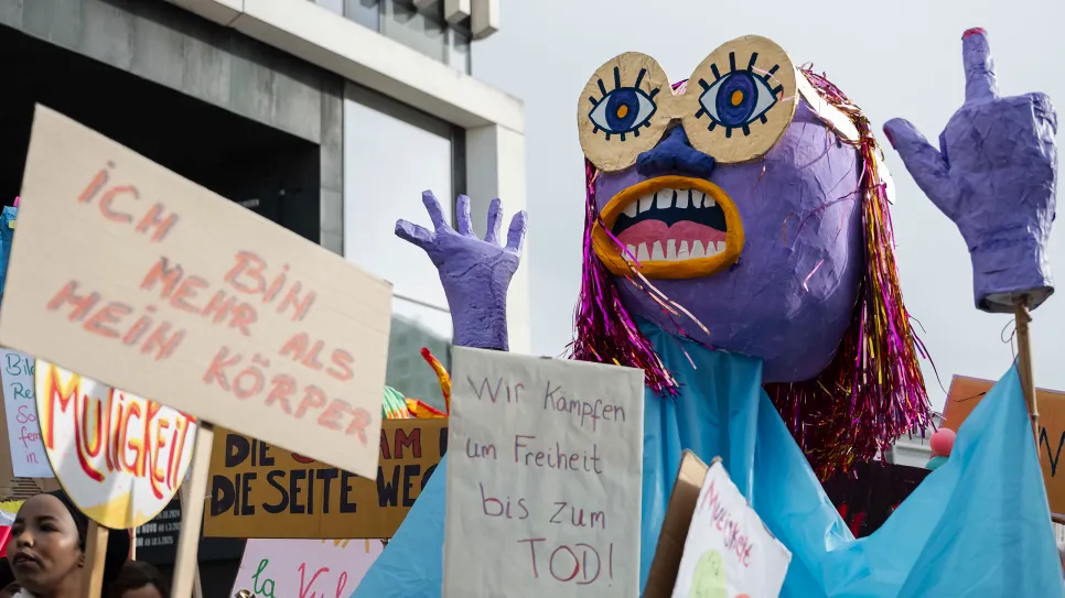 Große Puppe und Schilder mit feministischen Botschaften bei einer Demonstration.