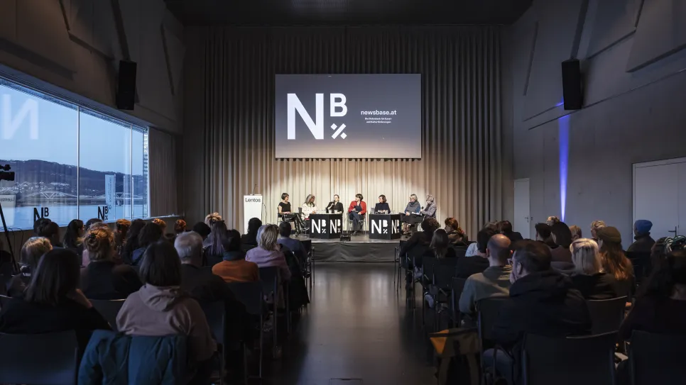 Podiumsdiskussion mit Publikum in einem modernen Veranstaltungsraum.