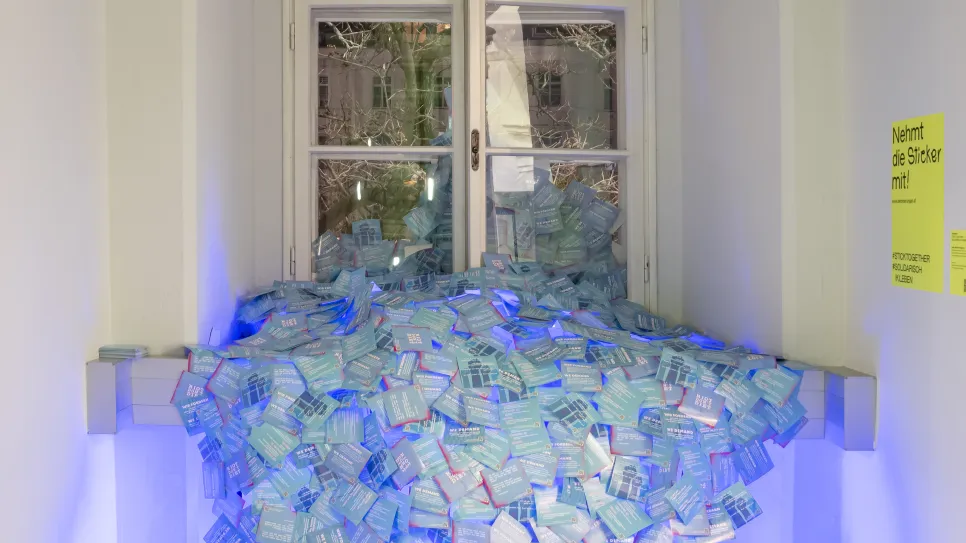 Blaue Lichtinstallation mit Pappkartons vor einem Fenster in einem Flur.