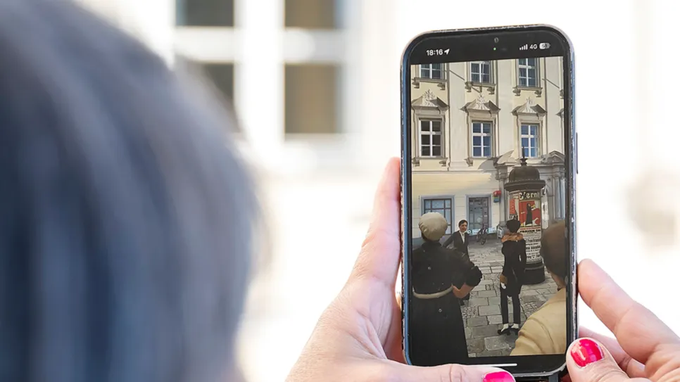 Hand hält Smartphone mit Foto von Frauenversammlung im Freien.
