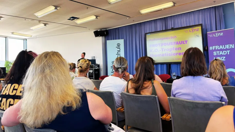Frauen sitzen in einem Konferenzraum, Präsentation über feministische Themen.