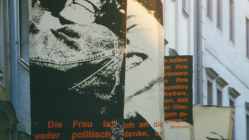 Fahnen mit feministischen Zitaten, in einer engen städtischen Straße aufgehängt.