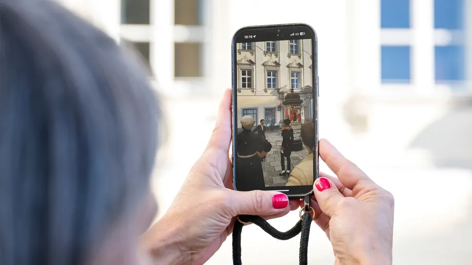 Smartphone-Foto einer Straßenszene, Frau mit roten Nägeln im Fokus.