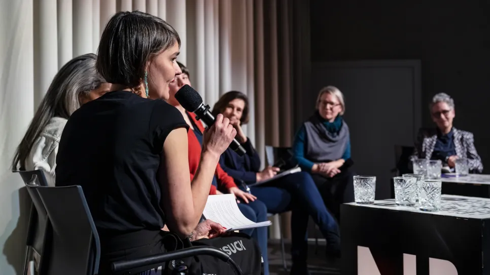 Podiumsdiskussion mit sechs Frauen, eine spricht ins Mikrofon.