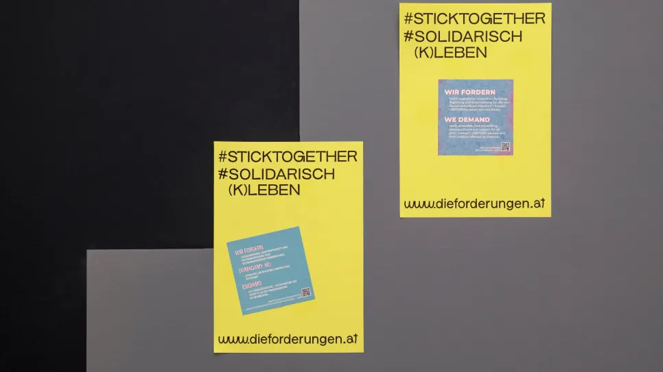 Gelbe Plakate mit Text, Hashtags und Website auf grauem Hintergrund.