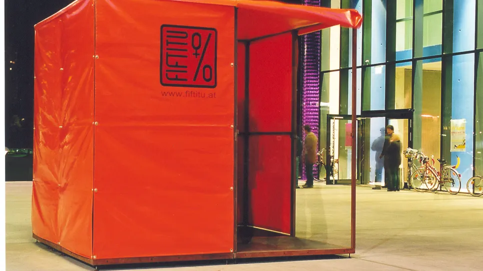 Rotes Zelt mit Fifty-Percent-Logo, beleuchtete Gebäude im Hintergrund.
