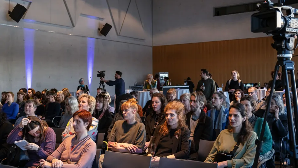 Publikum in einem Konferenzraum, aufmerksam lauschend.