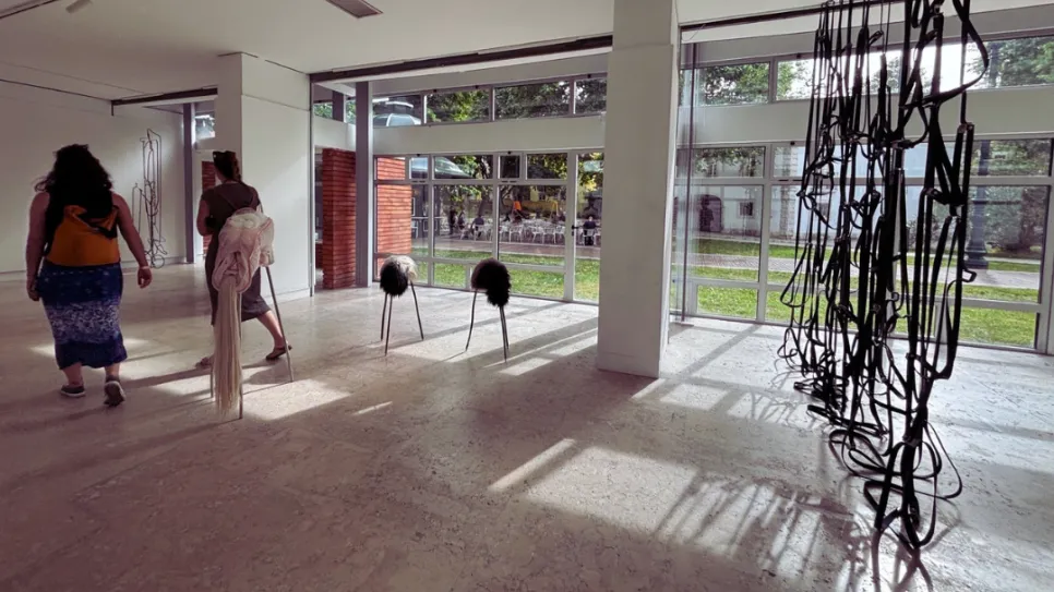 Kunstgalerie mit Skulpturen, große Fenster, drei Personen laufen im Licht.
