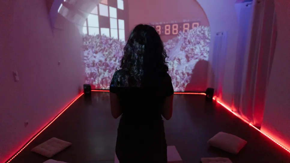 Person in dunklem Raum, Video-Projektion an der Wand.