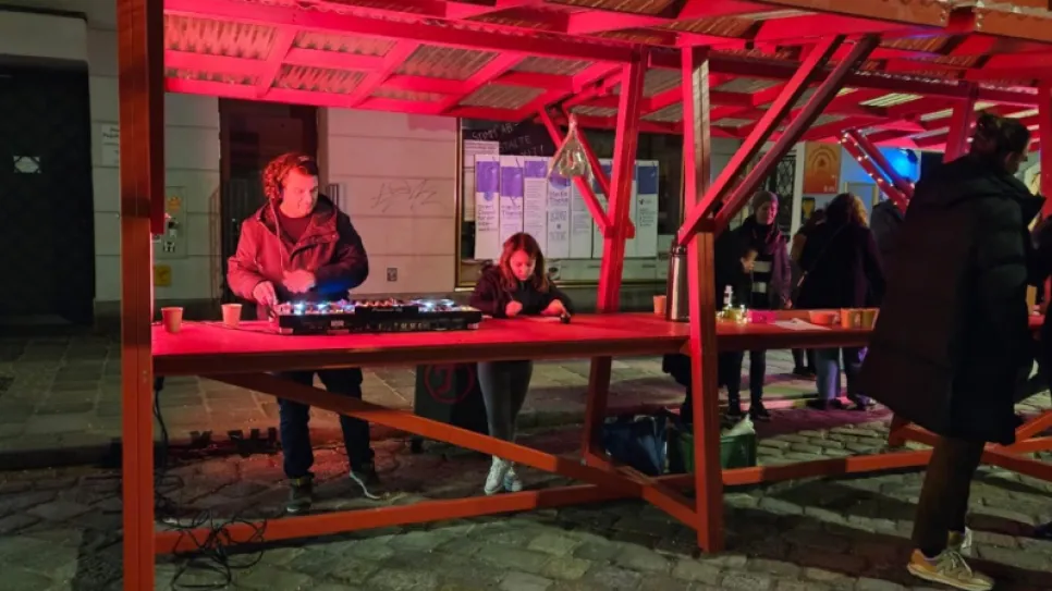 Veranstaltung am Abend, rote Beleuchtung, Personen an einem Stand draußen.
