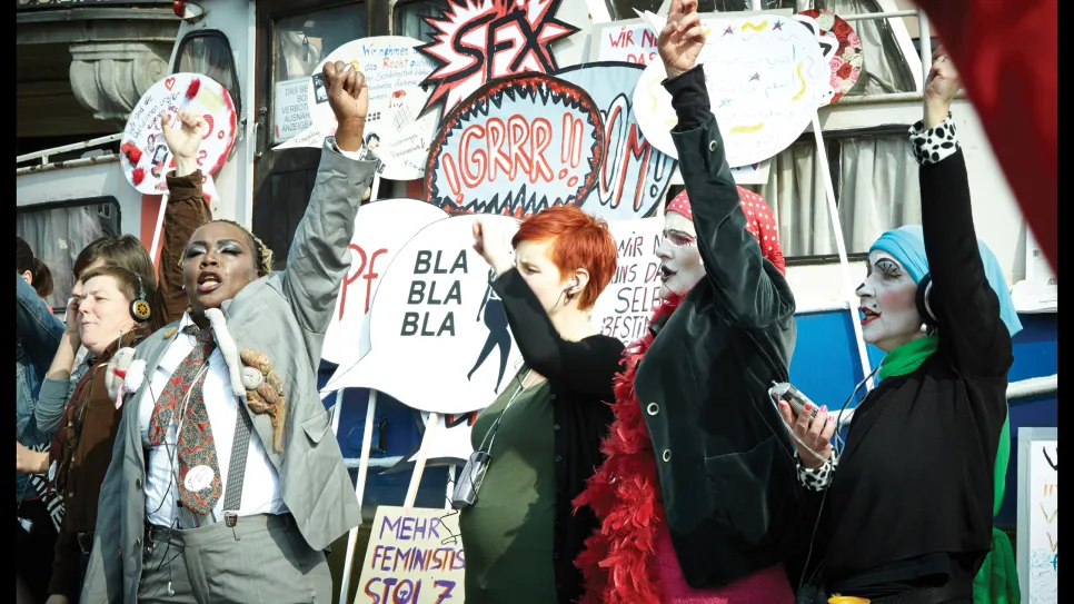 Personen auf einer Demonstration mit erhobenen Fäusten und Plakaten.