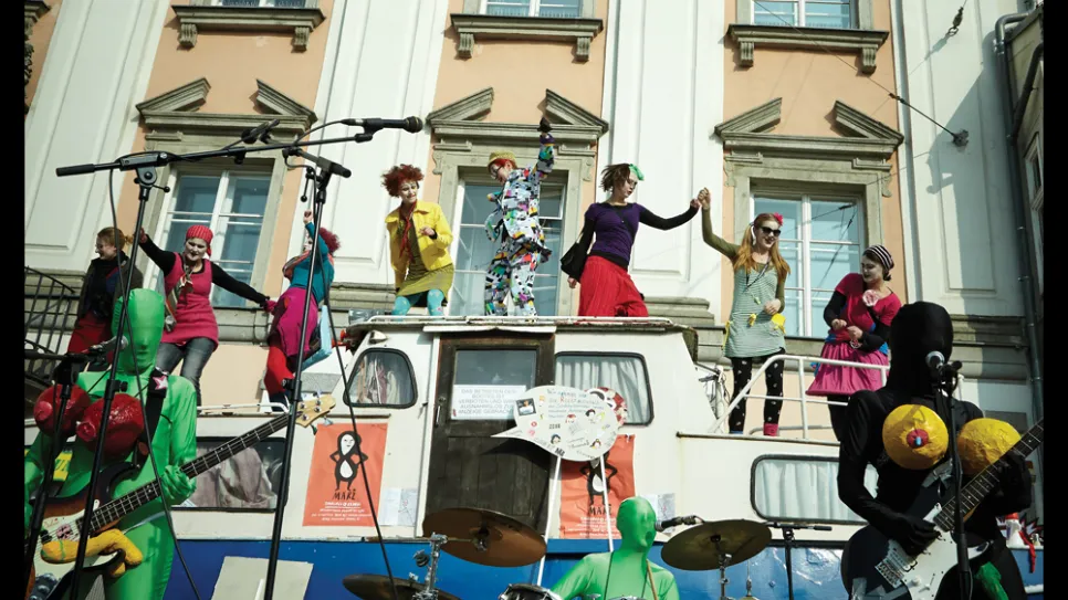 Straßenperformance vor einem historischen Gebäude, Kostüme und Band im Vordergrund.