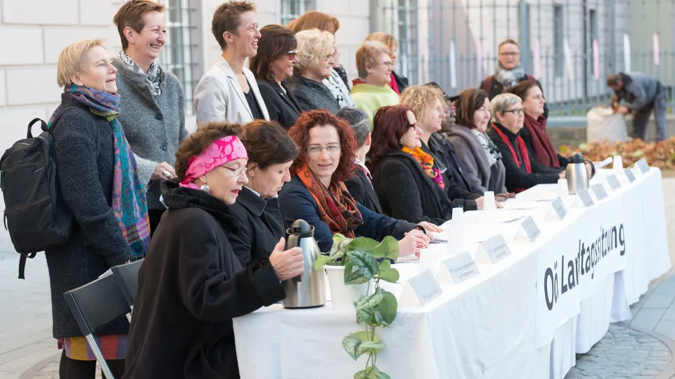 Frauen bei einer Versammlung im Freien, Tisch mit der Aufschrift "Ökumenische Frauenorganisation".