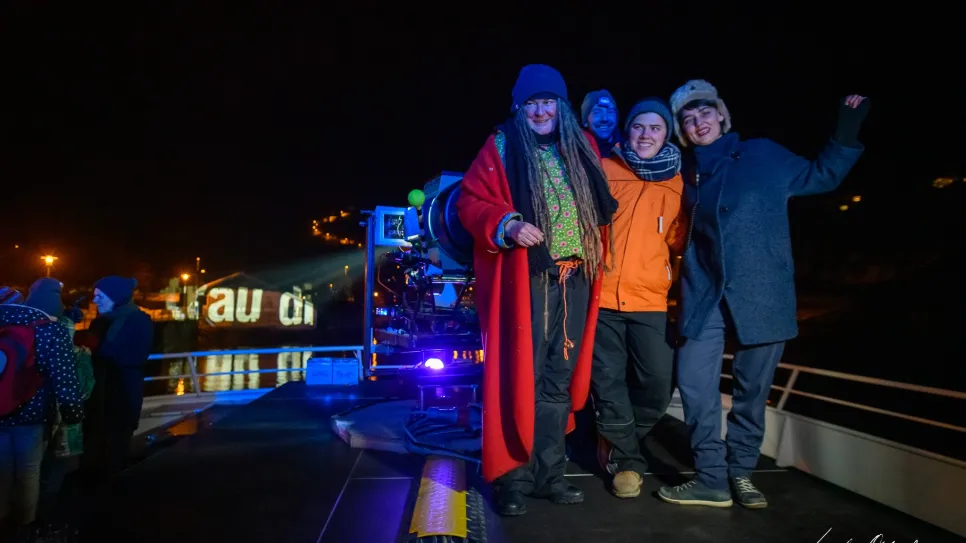 Menschen in Winterkleidung auf einem beleuchteten Boot bei Nacht.
