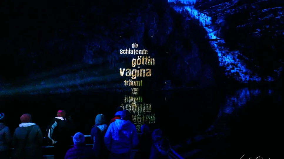 Personengruppe bei Nacht, Lichtprojektion mit feministischen Wörtern auf einem Hügel.