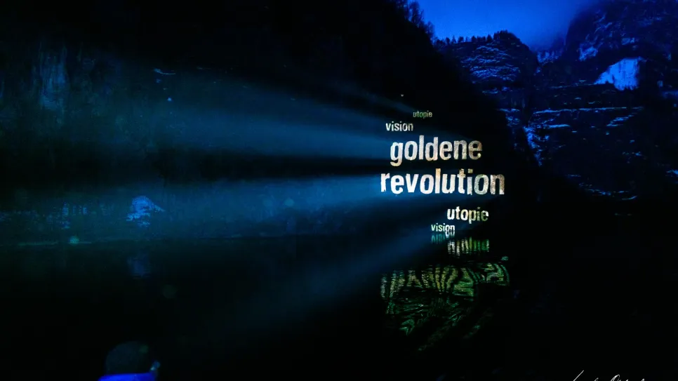 Lichtprojektion von Worten auf Bergkulisse bei Nacht.