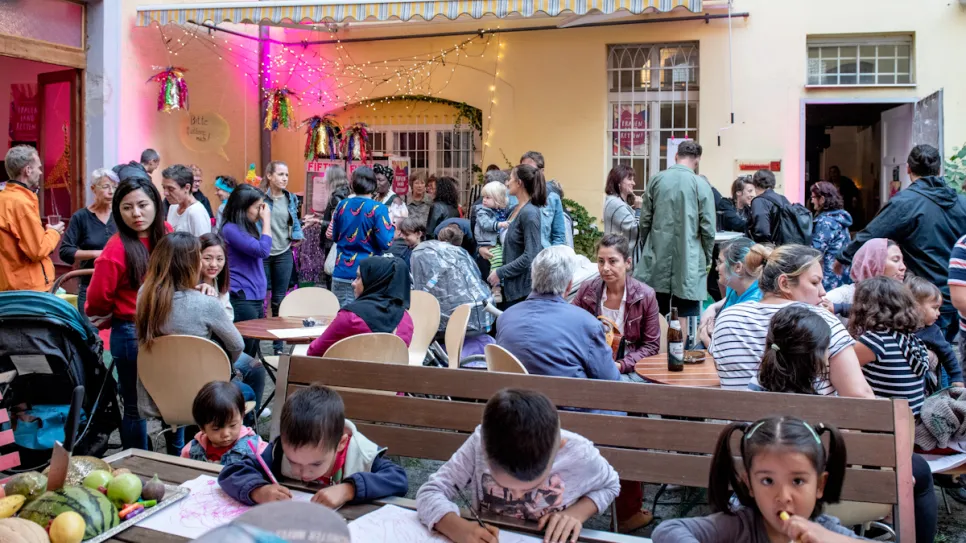 Menschen bei Gemeinschaftsveranstaltung im Innenhof, Kinder zeichnen.