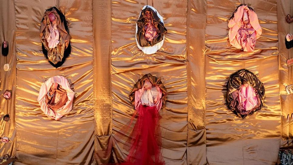 Kunstinstallation mit rotem Stoff und goldener Kulisse.