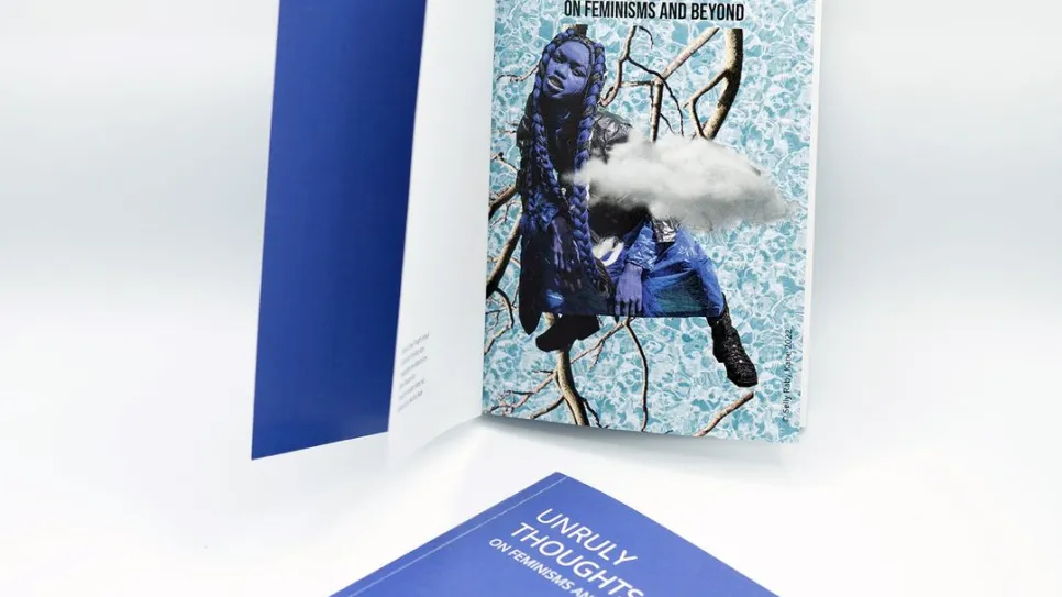 Offenes Buch und Heft mit blauem Einband auf hellem Hintergrund.