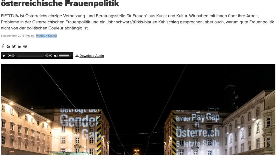 Fotografie: Nachtaufnahme einer belebten Straße mit beleuchteten Gebäuden.