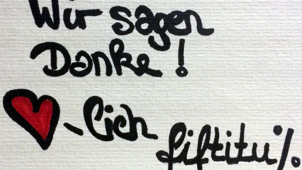 Danke-Nachricht mit rotem Herz, handgeschrieben auf weißem Hintergrund.