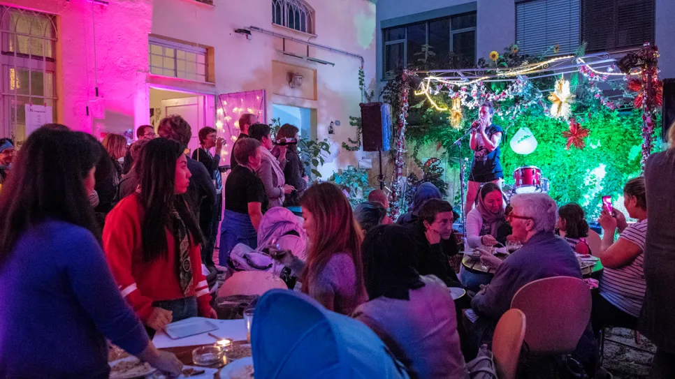 Bunt erleuchtetes Fest mit vielen Menschen im Innenhof bei Nacht.