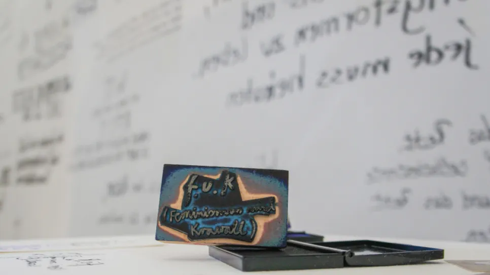 Stempel auf Tisch vor beschrifteter Wand, Unschärfe im Hintergrund.