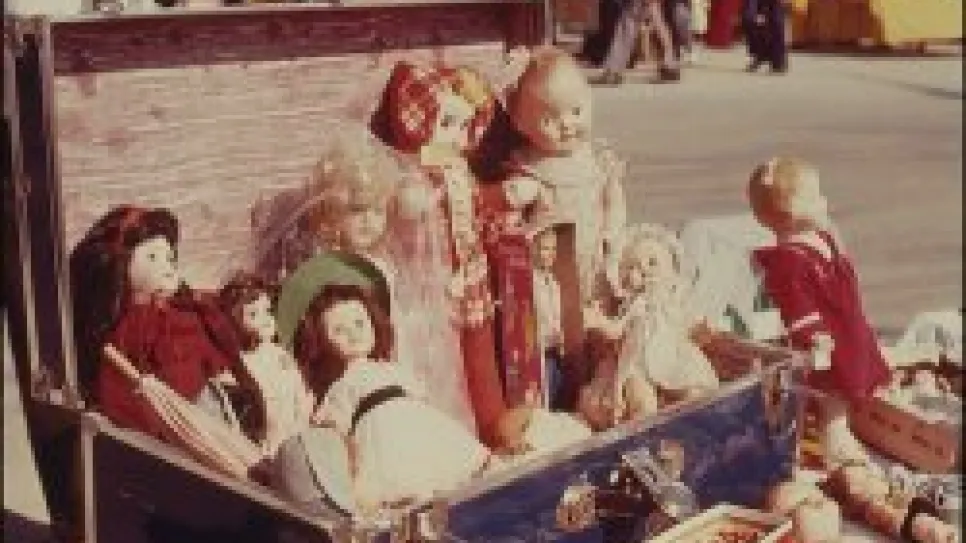 Antike Puppen in einem offenen Koffer auf einem Flohmarkt.