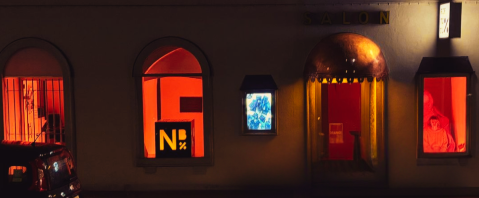 Gebäude bei Nacht mit oranger Beleuchtung und Schaufenstern zu den 16 Tagen gegen geschlechterspezifische Gewalt