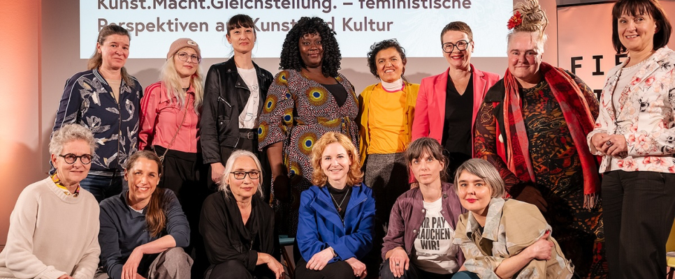 Gruppe von Frauen vor einem Banner mit dem Titel "Kunst. Macht. Gleichstellung."