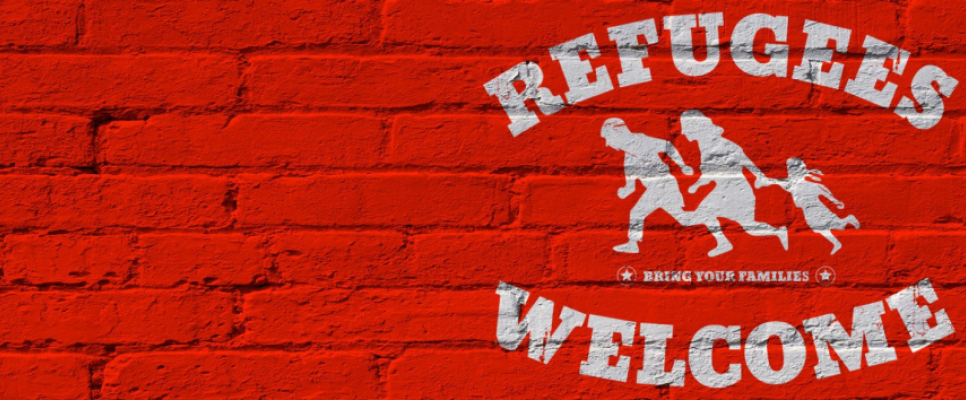 Rote Ziegelwand mit Grafik einer Flüchtlingsfamilie und Text "Refugees Welcome".