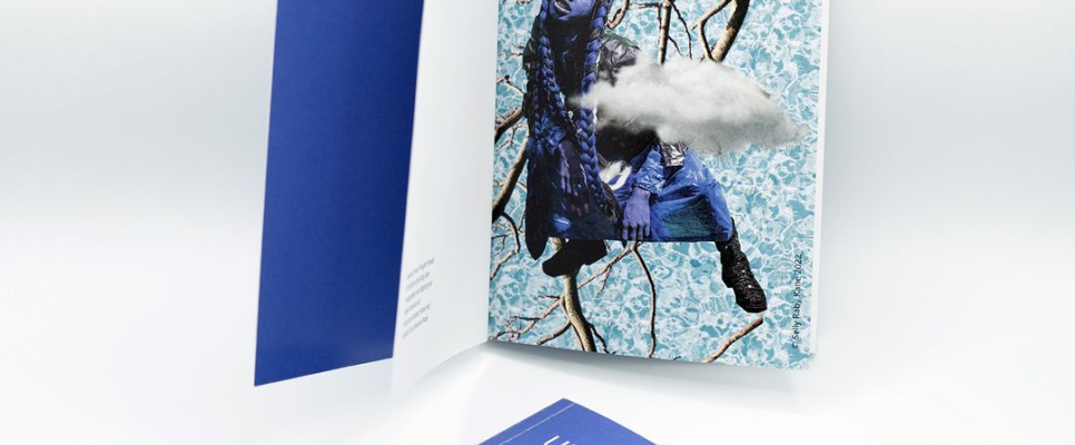 Offenes Buch und Heft mit blauem Einband auf hellem Hintergrund.