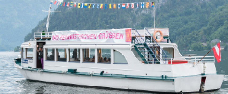 Weißes Boot auf einem See mit Bergen im Hintergrund.