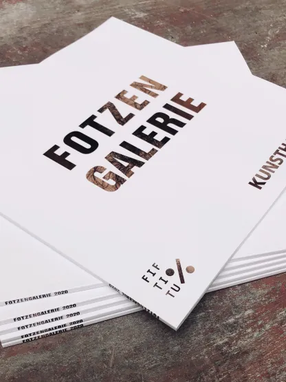 Broschürenstapel mit Aufschrift "Fotzen Galerie Kunsthalle".