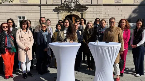 Viele Frauen stehen rund um die Stehtische bei der Pressekonferenz.