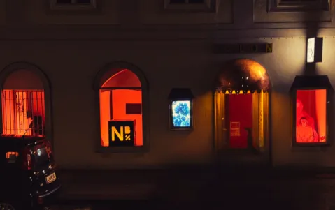 Gebäude bei Nacht mit oranger Beleuchtung und Schaufenstern zu den 16 Tagen gegen geschlechterspezifische Gewalt