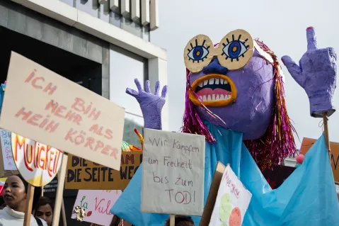 Große Puppe und Schilder mit feministischen Botschaften bei einer Demonstration.