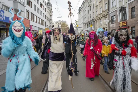 Menschen in bunten Kostümen und Masken bei einem Straßenumzug.