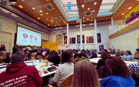 Teilnehmer in einem Konferenzraum, blicken auf eine Präsentation.