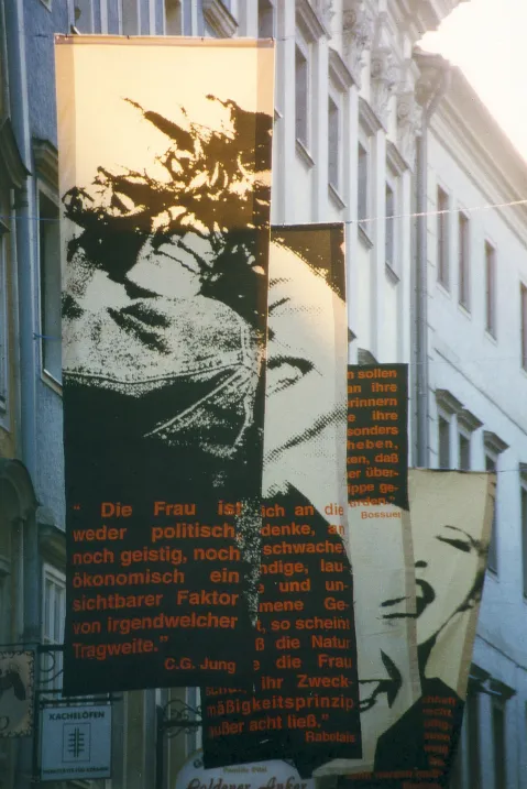 Fahnen mit feministischen Zitaten, in einer engen städtischen Straße aufgehängt.