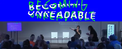 Bühne mit Vortrag, blauer Hintergrund, Publikum, Schriftzug "Becoming Unreadable".