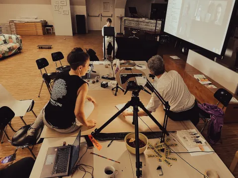 Personen bei Workshop mit Laptop und Leinwand im Raum.
