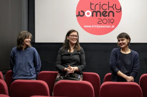 Drei Frauen lächeln vor einer Kinoleinwand mit "tricky women 2019"-Logo.
