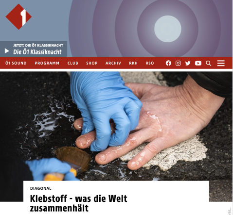Zwei Hände, eine mit blauen Handschuhen, kleben etwas auf Asphalt.