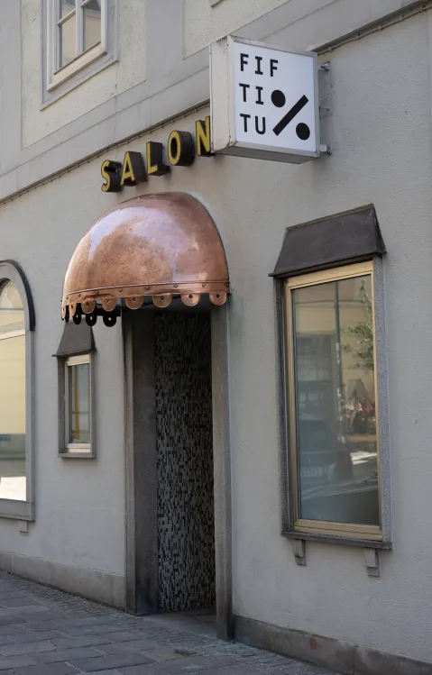 Gebäudeeingang mit Kupferdach, Schild und Fenster.