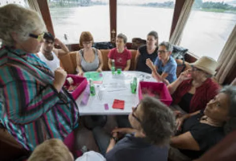 Mehrere Personen sitzen an einem Tisch auf einem Boot, diskutierend und entspannt.
